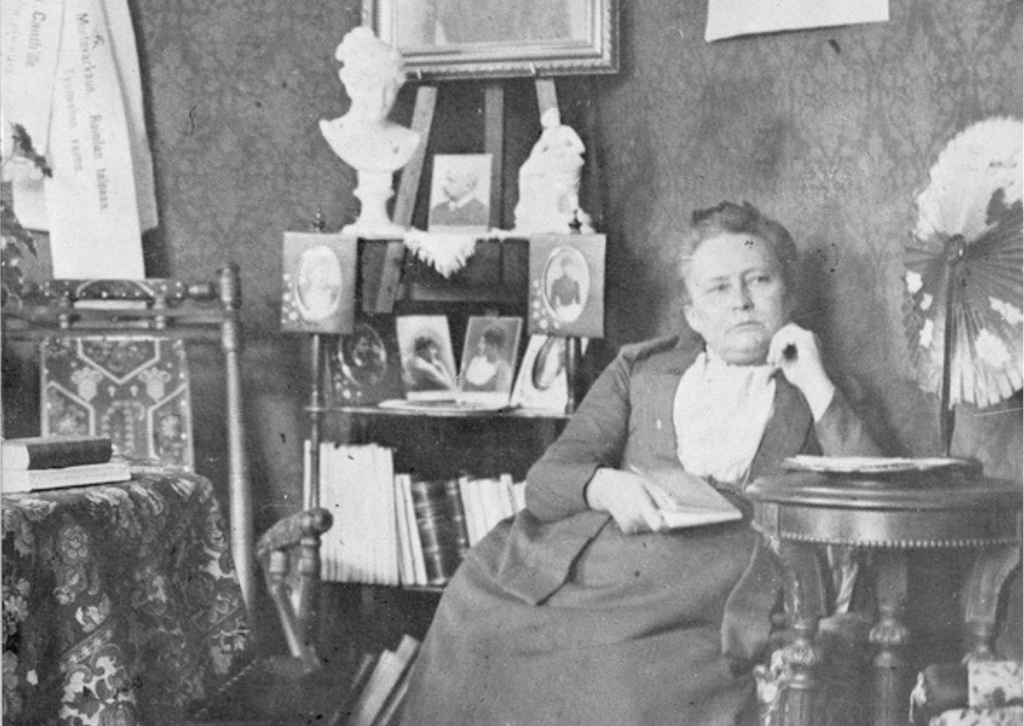 Kuvassa Minna Canth istumassa salongissaan. Kuva on vuodelta 1891. 